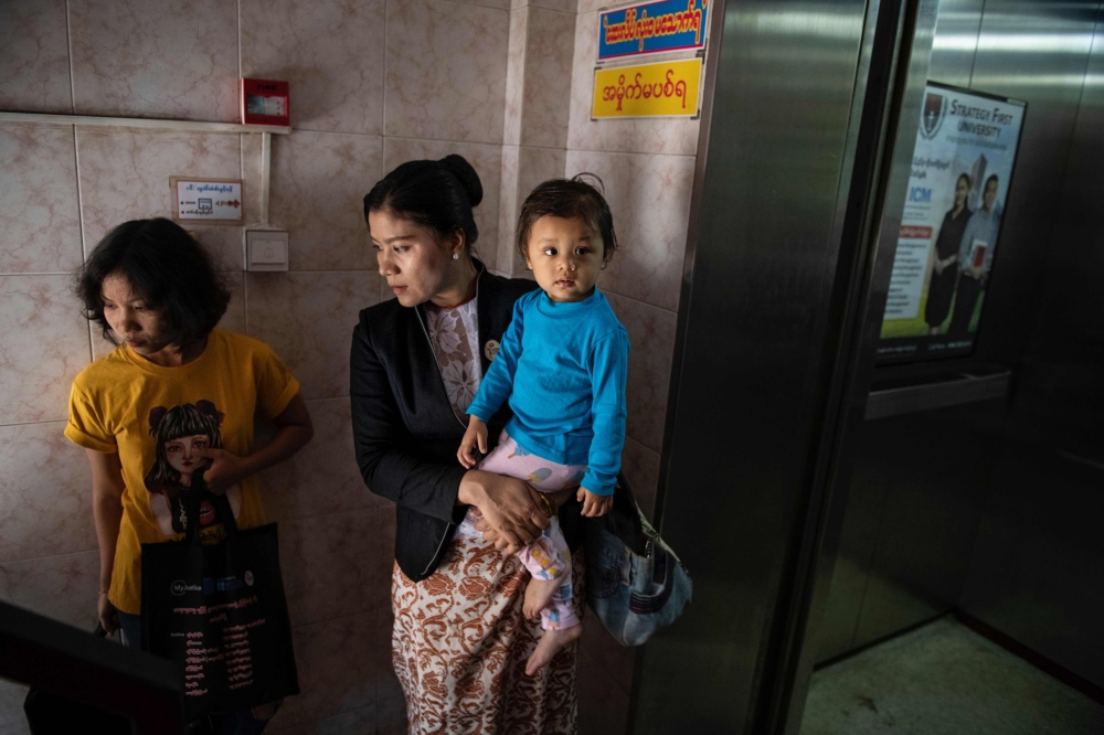 Legal Clinic Myanmar director Hla Hla Yee (C) carrying her daughter before a meeting at the Gender Equality Network office in Yangon February 11, 2020. AFP / Shwe Paw Mya Tin
