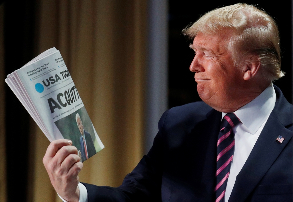 File photo: Donald Trump holds up a copy of USA Today front page news of his acquittal in his impeachment trial as he arrives to address the National Prayer Breakfast in Washington, February 6, 2020. Reuters / Leah Millis