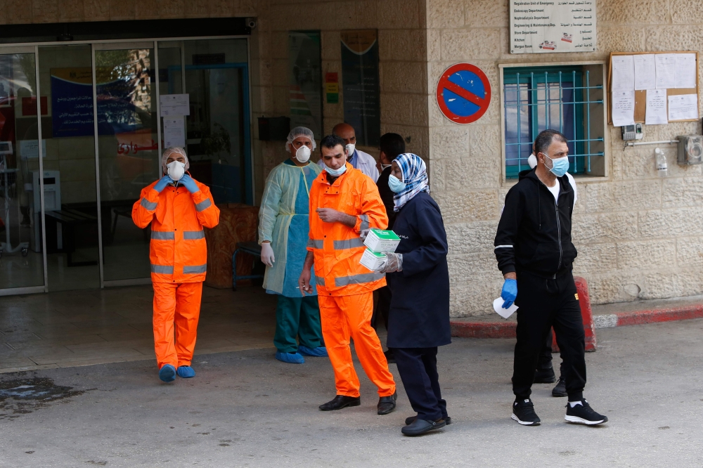 Palestinian staff stand at the emergency entrance of Beit Jala Hospital on March 9, 2020, near the West Bank city of Bethlehem which is under lockdown due to the novel coronavirus epidemic. AFP / Musa Al Shaer
 