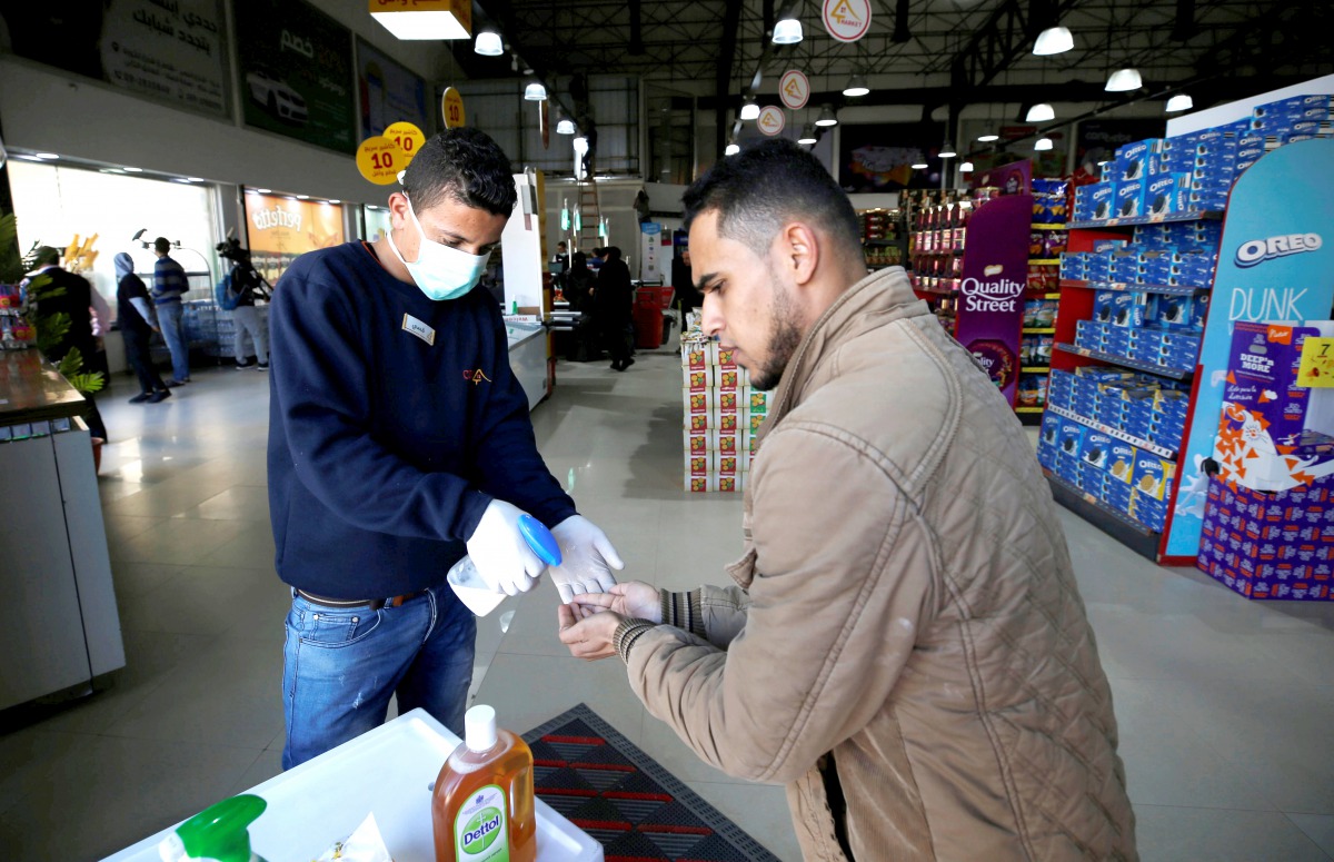 A Palestinian worker wearing a mask sanitizes the hands of a customer amid coronavirus precautions, in a supermarket in Gaza City March 8, 2020. Reuters/Mohammed Salem