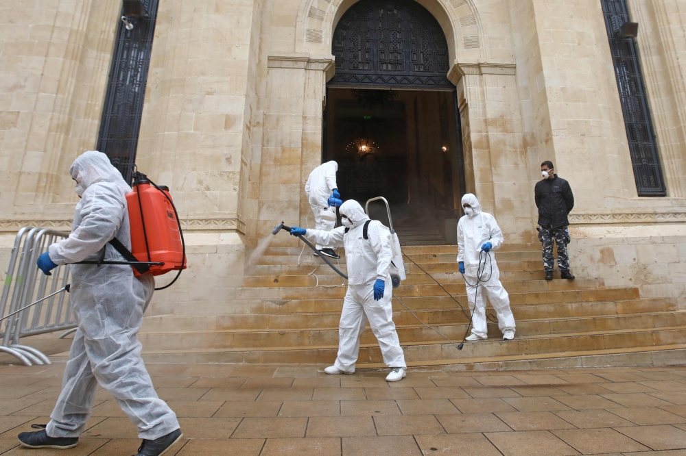Sanitary workers disinfect the entrance of the Lebanese Parliament in central Beirut on March 10, 2020, amid the spread of coronavirus in the country. / AFP / ANWAR AMRO