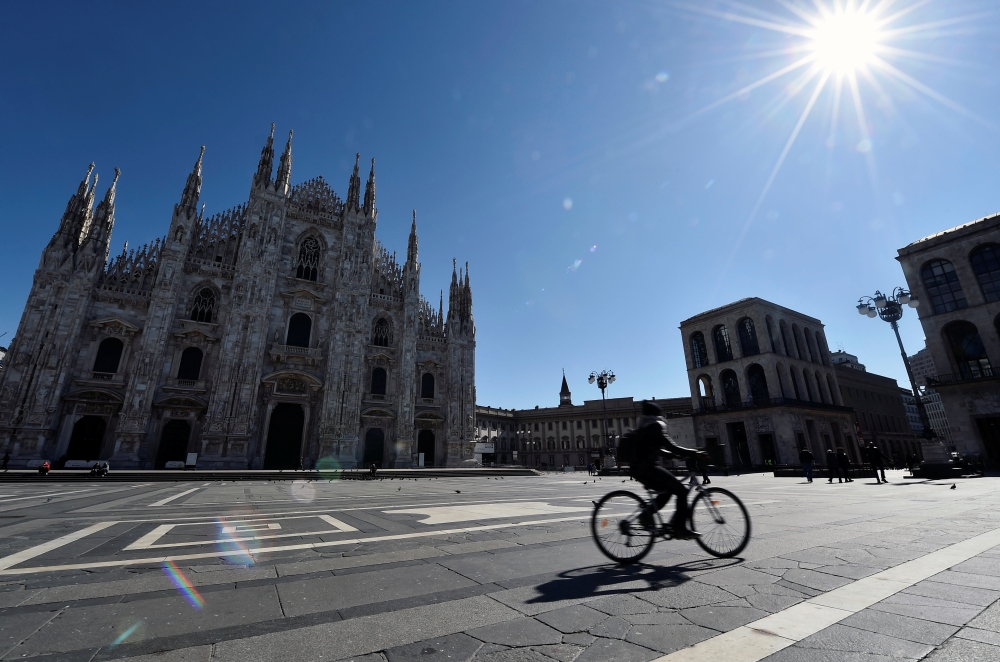 A person rides a bicycle past Milan Cathedral on the second day of an unprecedented lockdown across all of the country, imposed to slow the outbreak of coronavirus, in Milan, Italy March 11, 2020. Reuters/Flavio Lo Scalzo