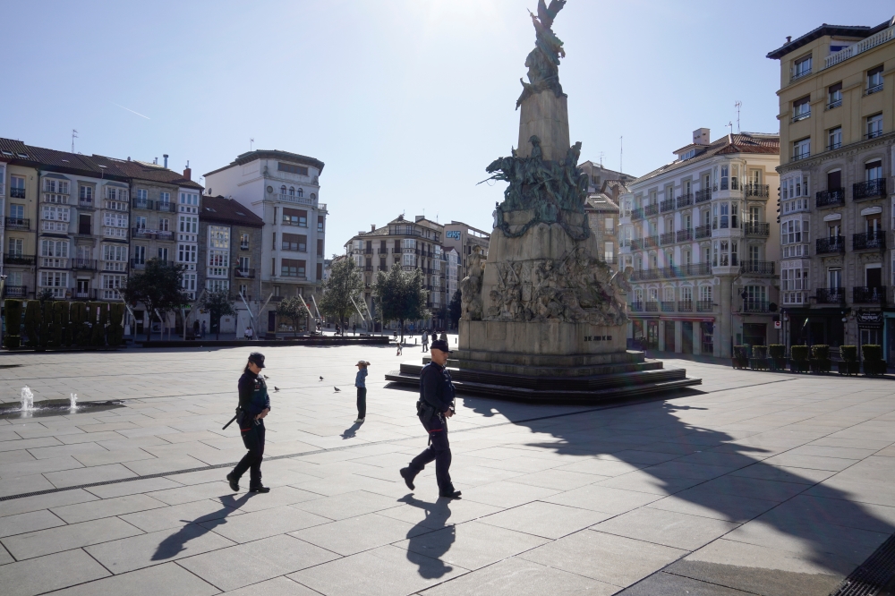 Police officers cross a virtually deserted square, amidst concerns over Spain's coronavirus outbreak, in the Basque city of Vitoria, Spain, March 14, 2020. REUTERS/Vincent West