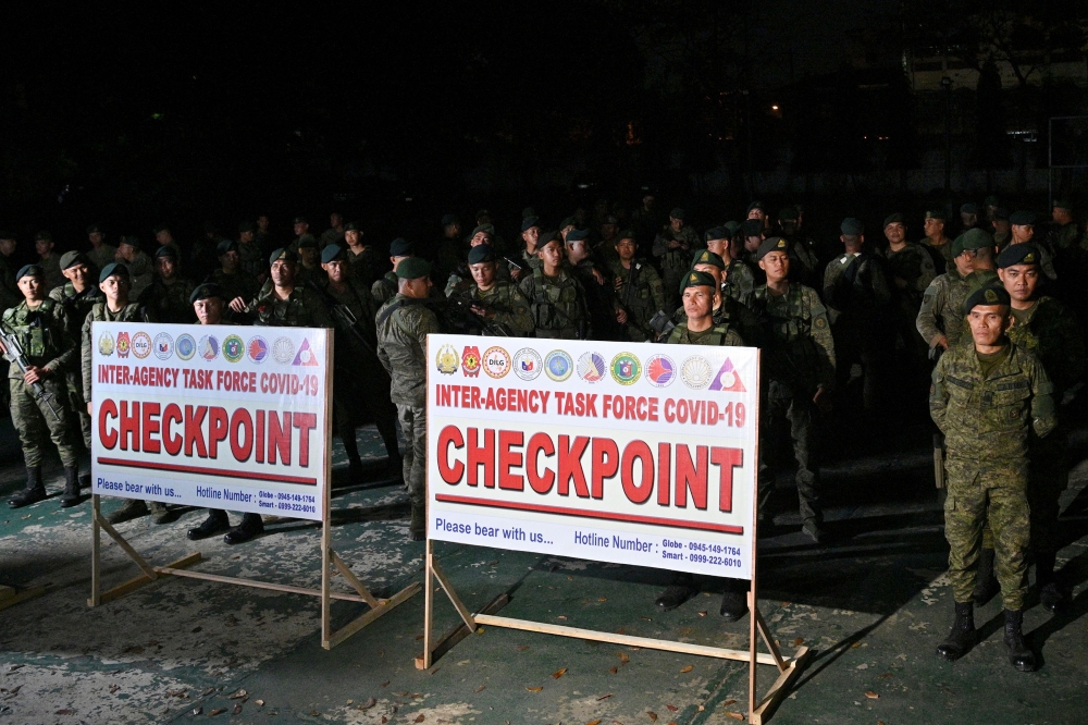 Soldiers stand guard as they wait inside the military headquarters to be deployed in major thoroughfares, in Manila on March 14, 2020.  / AFP / Ted ALJIBE 