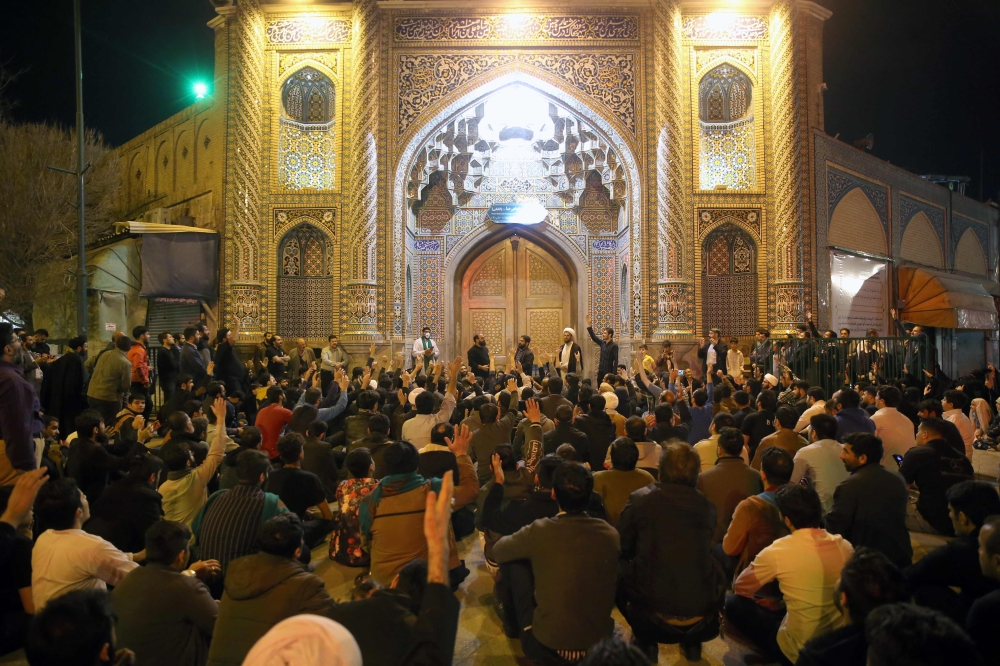 People gather outside the closed doors of the Fatima Masumeh shrine in Iran's holy city of Qom on March 16 2020. AFP / MEHDI MARIZAD