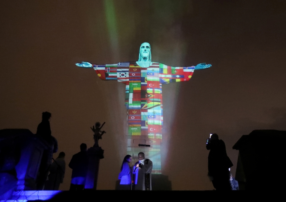 The statue of Christ the Redeemer is lit up in the colors of the countries that are affected by the coronavirus disease (COVID-19) outbreak in Rio de Janeiro, Brazil, March 18, 2020. REUTERS/Sergio Moraes