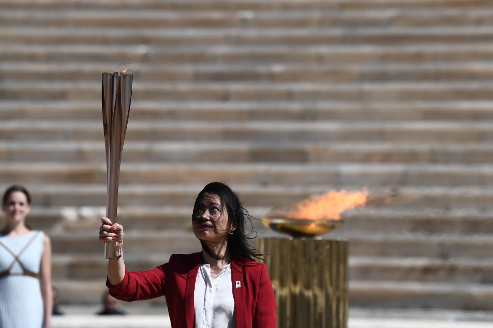 ATHENS, GREECE - MARCH 19: Former Japanese swimmer Imoto Naoko holds the Olympic torch during the olympic flame handover ceremony for the 2020 Tokyo Summer Olympics, on March 19, 2020 in Athens. T ( ARIS MESSINIS / AFP / Pool - Anadolu Agency )