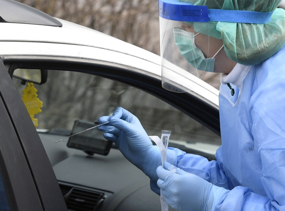A medical member in protective clothing takes samples at a testing drive-in station for the health and hospital professionals where people can get tested for the novel coronavirus disease (COVID-19) directly from their cars, in Espoo, Finland March 18, 20