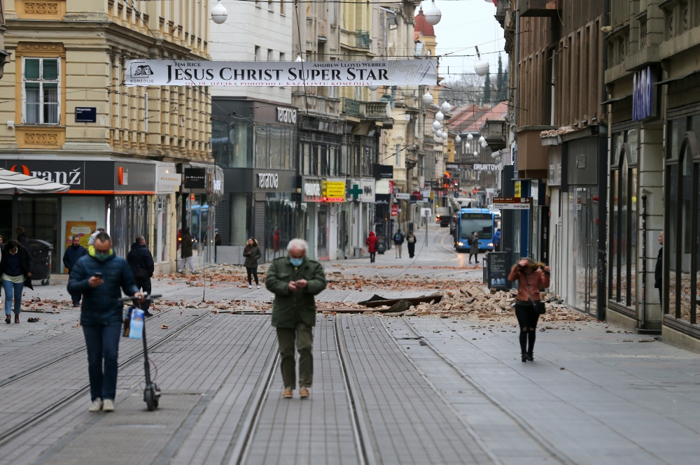 People walk past debris in a street after an earthquake, in Zagreb, Croatia March 22, 2020. REUTERS/Antonio Bronic
