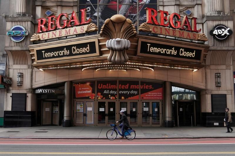 FILE PHOTO: A man cycles past a shuttered movie theater in Times Square following the outbreak of coronavirus disease (COVID-19), in the Manhattan borough of New York City, New York, U.S., March 17, 2020. REUTERS/Carlo Allegri