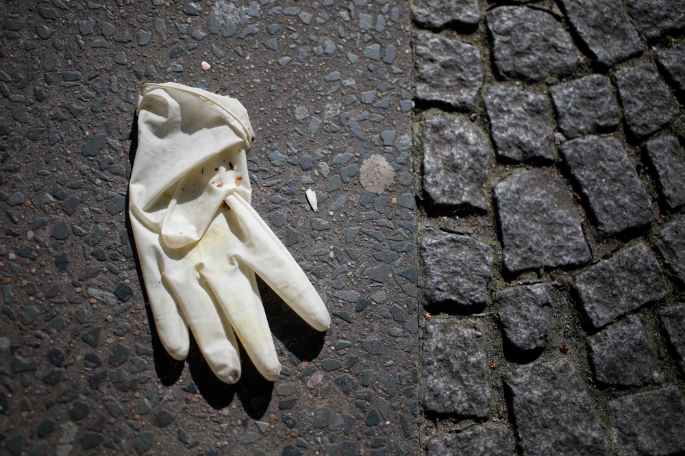A thrown-away protective glove lays on the pavement in Berlin's Kreuzberg district on March 23, 2020, amidst the new coronavirus COVID-19 pandemic. AFP / David Gannon 