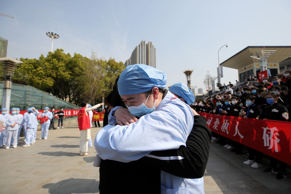 A local medical worker embraces and bids farewell to a medical worker from Jiangsu at the Wuhan Railway Station as the medical team from Jiangsu leaves Wuhan, the epicentre of the coronavirus disease (COVID-19) outbreak, in Hubei province, China March 19,