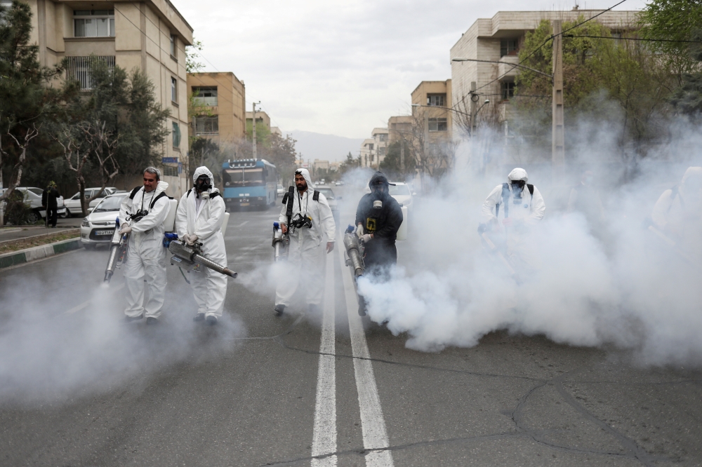 FILE PHOTO: Members of firefighters wear protective face masks, amid fear of coronavirus disease (COVID-19), as they disinfect the streets, ahead of the Iranian New Year Nowruz, March 20, in Tehran, Iran March 18, 2020. Picture taken March 18, 2020. WANA 