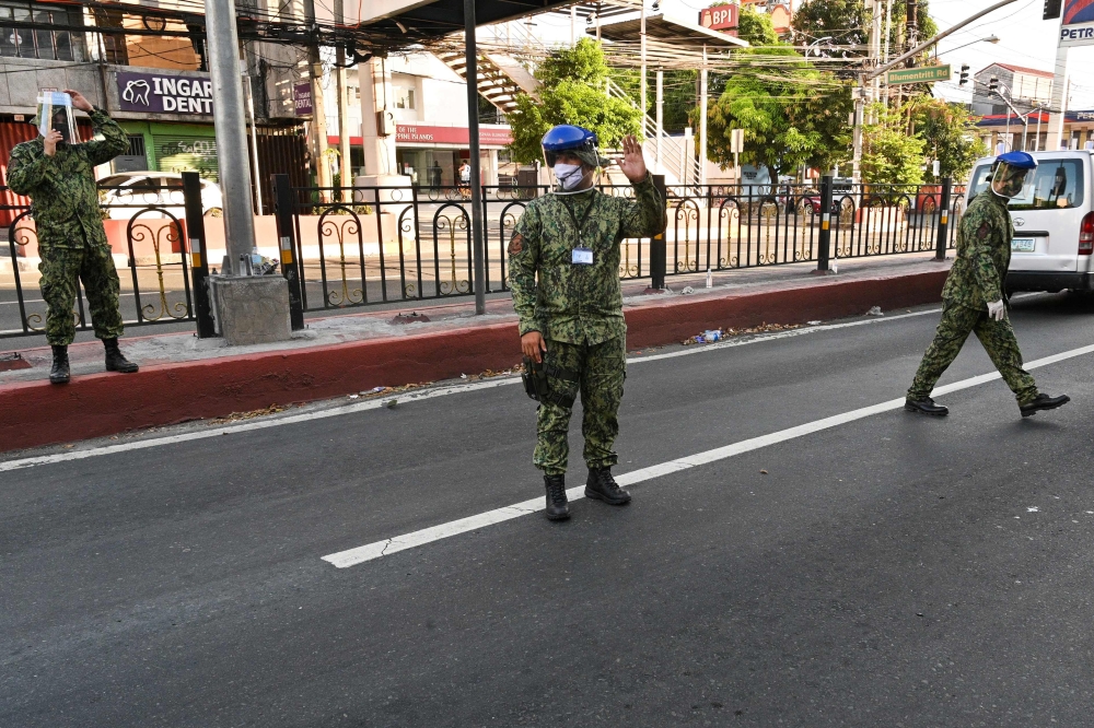Philippine policemen wearing facemasks man a checkpoint after the government imposed an enhanced quarantine as a preventive measure against the COVID-19 novel coronavirus in Manila on March 25, 2020. / AFP / Ted ALJIBE