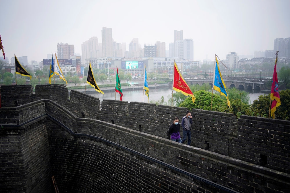 People wearing face masks walk on an ancient city wall in Jingzhou, after the tourist attraction reopened as the lockdown was eased in Hubei province, the epicentre of China's coronavirus disease (COVID-19) outbreak, March 26, 2020. Picture taken March 26