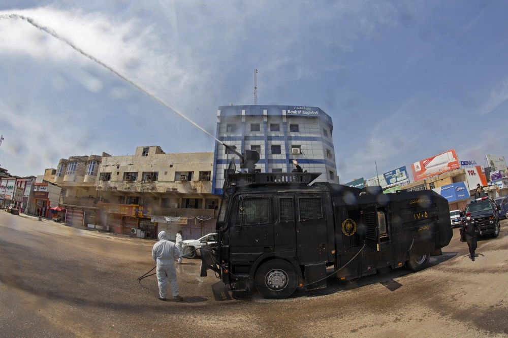 Iraqis use an anti-riot water-cannon vehicle to spray disinfecting liquid in the streets of the centre of the southern city of Basra on March 25, 2020, in a bid to slow down the spread of the novel coronavirus that causes the COVID-19 disease. / AFP / Hus