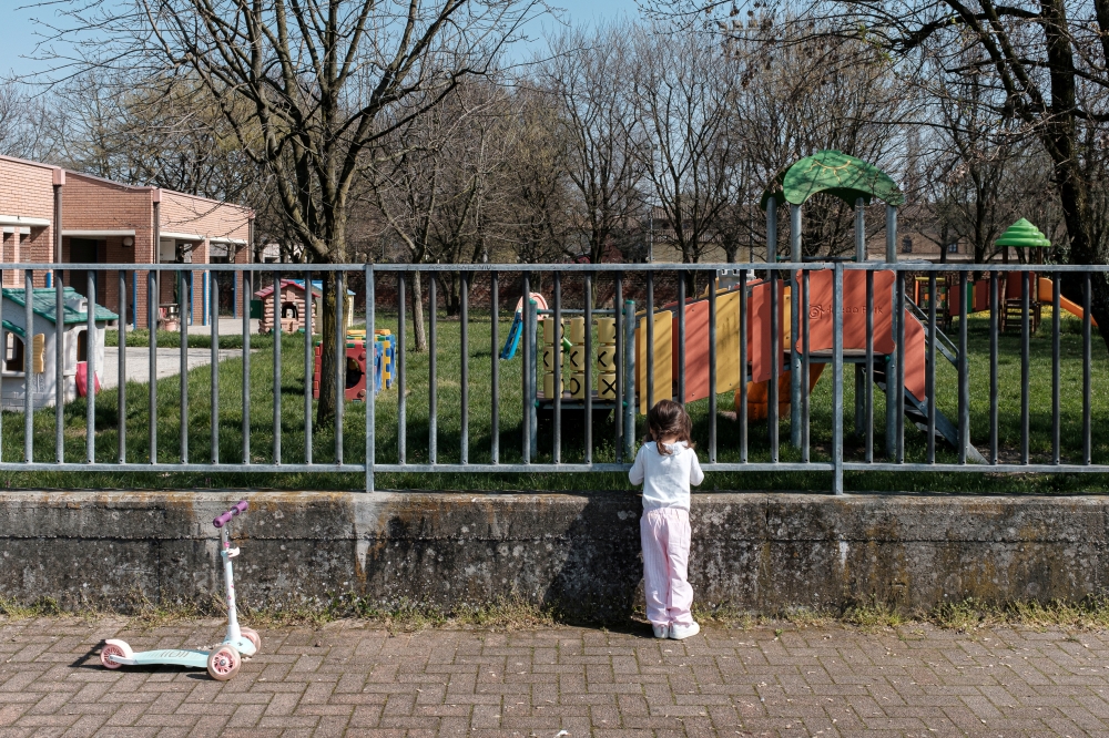Life in lockdown: Two-year-old Bianca Toniolo looks through the gates of a closed playground close to her home in San Fiorano, one of the original 'red zone' towns in northern Italy that has now been extended to whole country, in this picture taken by her