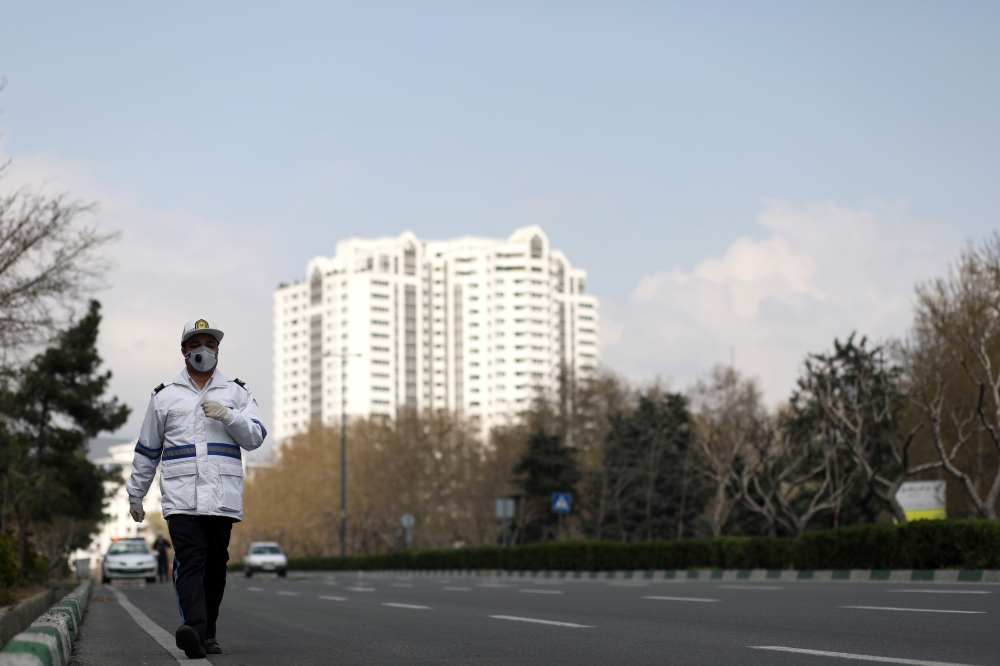 A traffic police officer wears a protective face mask and gloves, amid fear of coronavirus disease (COVID-19), as he walks in Tehran, Iran March 26, 2020. WANA (West Asia News Agency)/Ali Khara via Reuters 