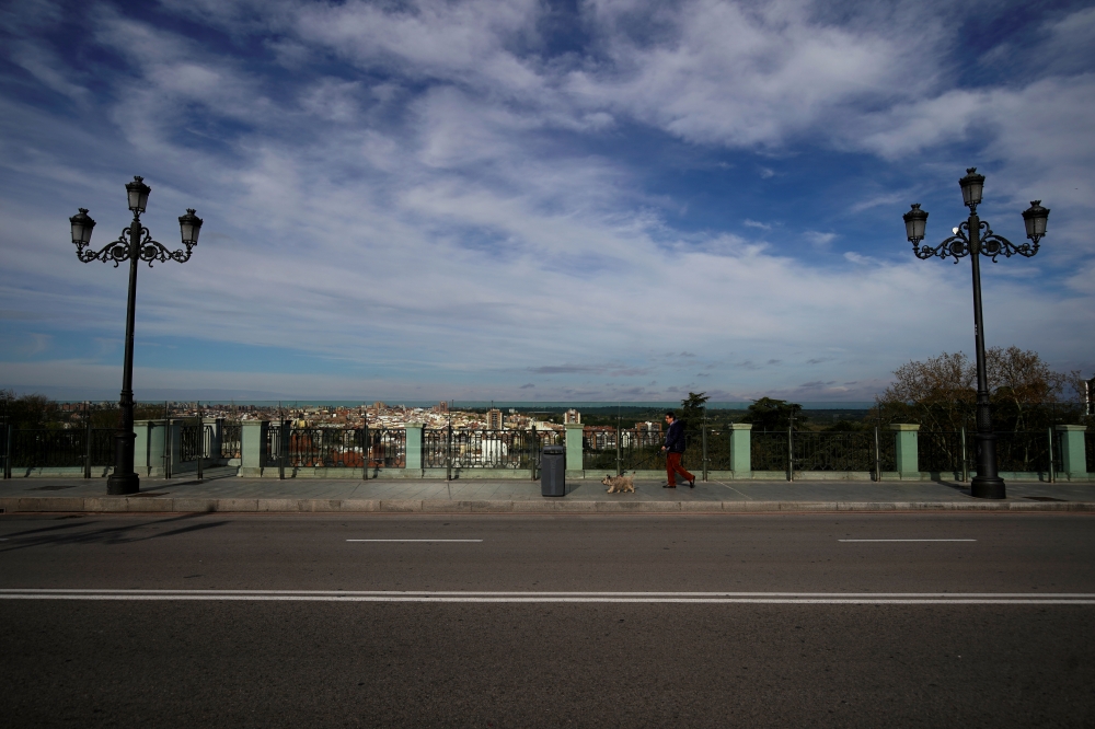 A man walks a dog along Segovia street during lockdown, amid the coronavirus disease (COVID-19) outbreak, in Madrid, Spain April 5, 2020. REUTERS/Juan Medina