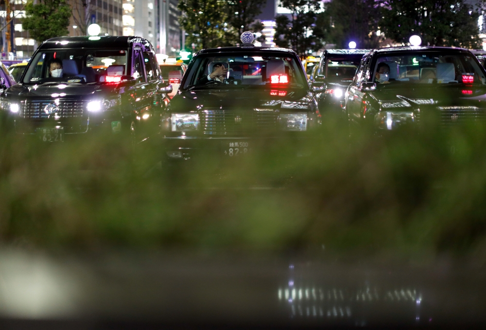 Drivers wearing protective face masks, following an outbreak of the coronavirus disease (COVID-19), are seen inside taxies at a taxi park in Tokyo, Japan April 3, 2020. REUTERS/Issei Kato

