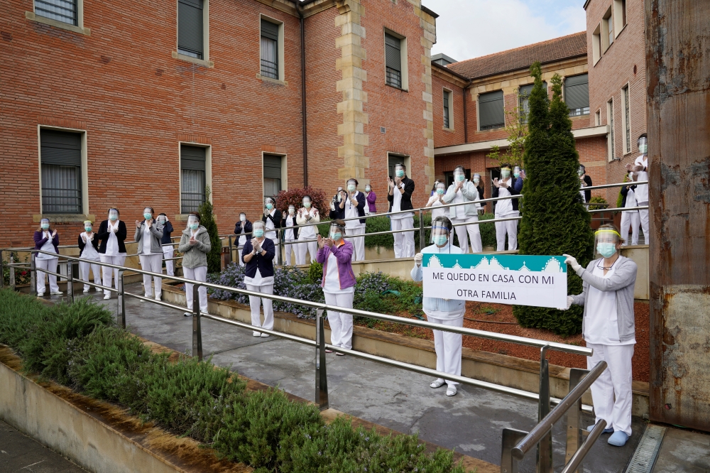 :Careworkers from the Juan Calzada nursing home stand behind a banner reading 