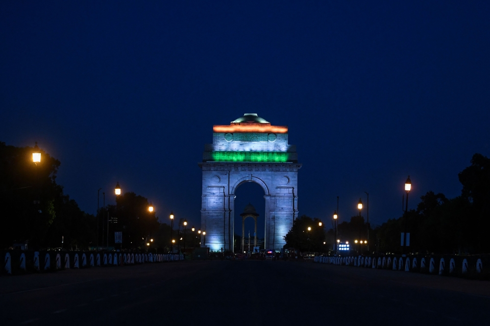 India gate is illuminated with the colors of the Indian national flag as seen from a deserted Rajpath during a government-imposed nationwide lockdown as a preventive measure against the COVID-19 coronavirus a in New Delhi on April 8, 2020. / AFP / Sajjad 