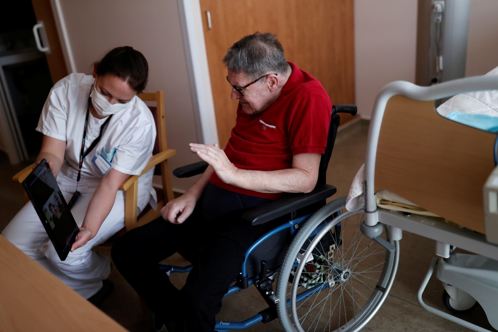 Health worker Emilie Neumann helps a 79 year-old resident to attend an online video call with his relatives at Les Jardins d'Emeraude long-term care unit at Bischwiller departemental hospital, near Strasbourg, during a lockdown imposed to slow the spread 