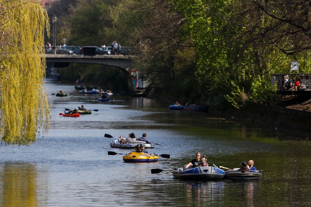 People paddle inflatable boats along the Landwehr canal in Berlin's Kreuzberg district as the sun shines on Easter Sunday, April 12, 2020 amid the novel coronavirus COVID-19 pandemic. / AFP / David GANNON