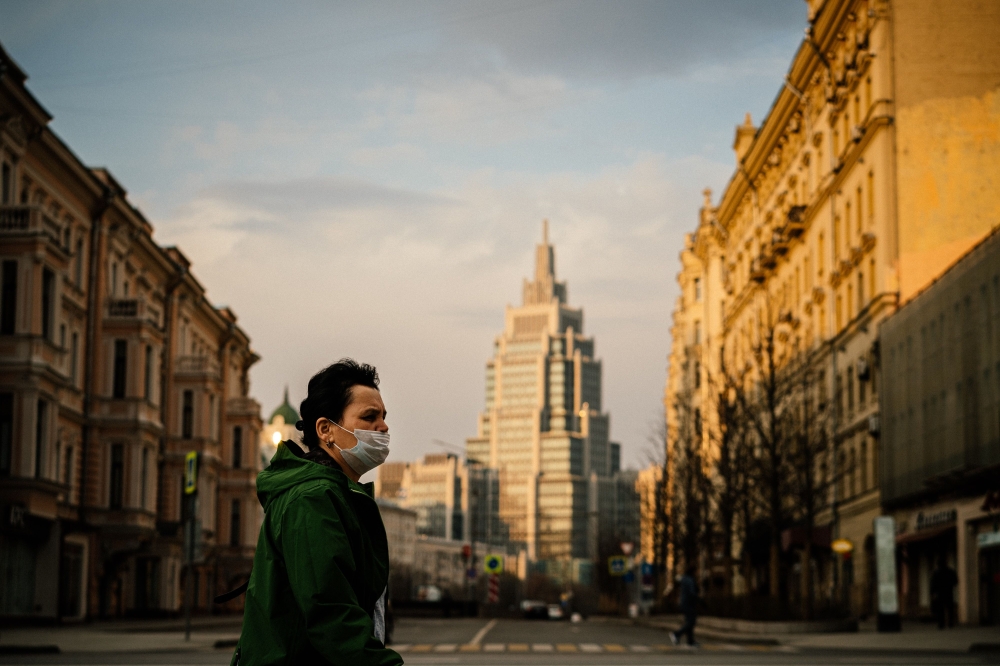 A woman wearing a face mask walks in a deserted street in central Moscow on April 13, 2020 during a strict lockdown in Russia to stop the spread of the COVID-19, caused by the novel coronavirus.  / AFP / Dimitar DILKOFF