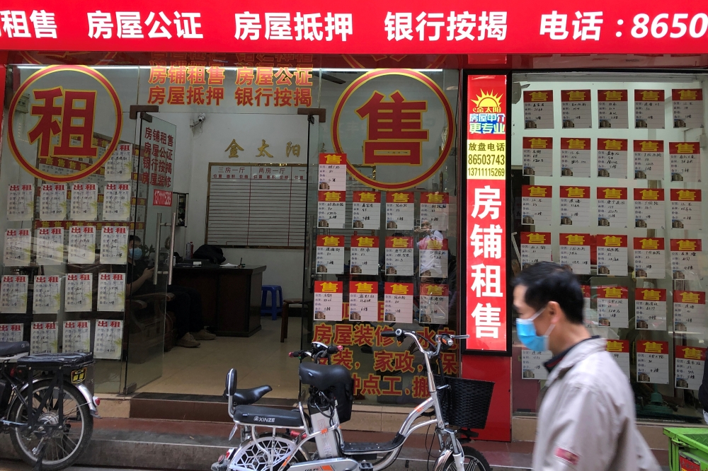 A man wearing a face mask walks past an estate agent in Guangzhou's Sanyuanli area, as the spread of the novel coronavirus disease (COVID-19) continues in the country, in Guangdong province, China April 13, 2020. Picture taken April 13, 2020. REUTERS/Davi