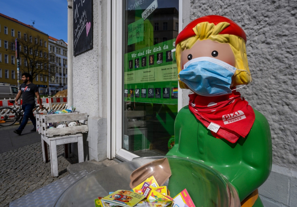 A lifesize promotional figure outside a bookstore has been fitted with a face cover in Berlin on April 16, 2020, amid a new coronavirus COVID-19 pandemic. / AFP / John MACDOUGALL
