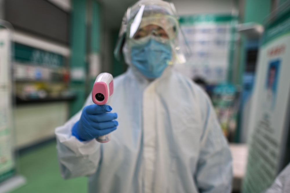 :TOPSHOT - A medical worker prepares to check the temperature of an AFP photojournalist before a COVID-19 coronavirus test in Wuhan in China's central Hubei province on April 16, 2020. / AFP / Hector RETAMAL
