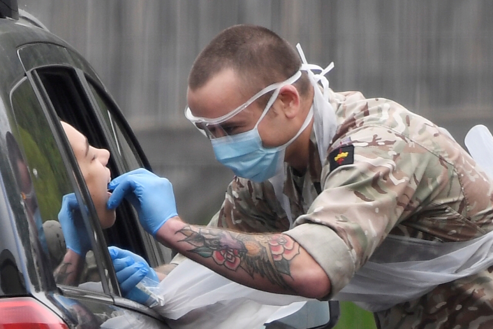 A member of the military tests a person at a coronavirus test centre in the car park of Chessington World of Adventures as the spread of the coronavirus disease (COVID-19) continues, Chessington, Britain, London, Britain, April 18, 2020. REUTERS/Toby Melv