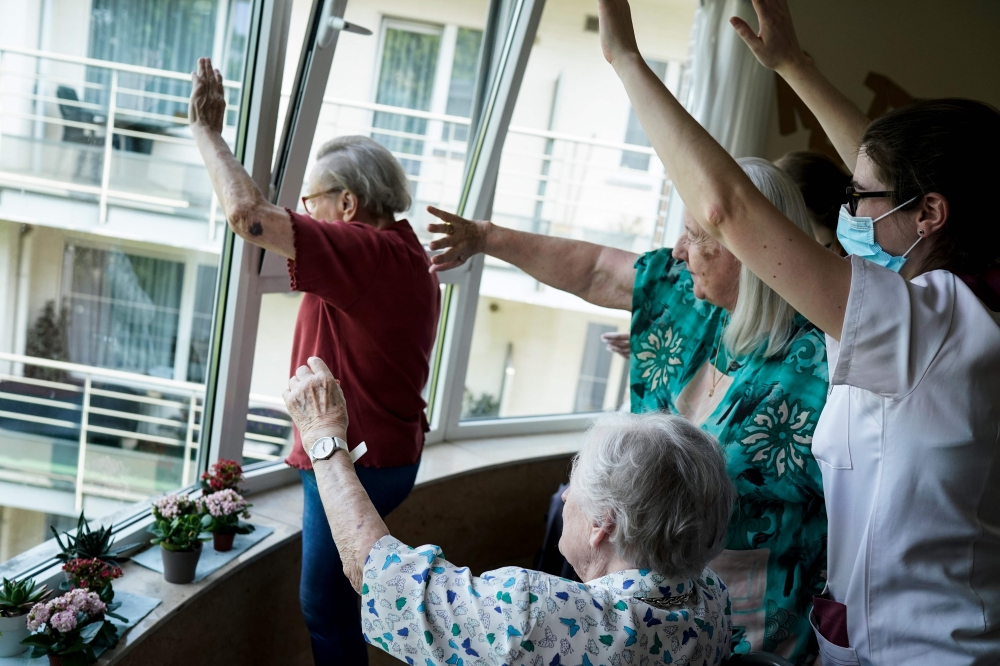 Staff members and residents salute their families at the elderly residence Christalain on April 17, 2020, in Brussels, during a strict lockdown in the country to fight against the novel coronavirus. / AFP / kenzo tribouillard