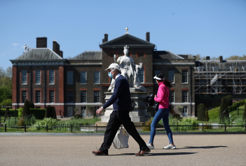 People wearing masks take a walk in Kensington Palace Park, as the spread of the coronavirus disease (COVID-19) continues, London, Britain, April 19, 2020. REUTERS/Simon Dawson
