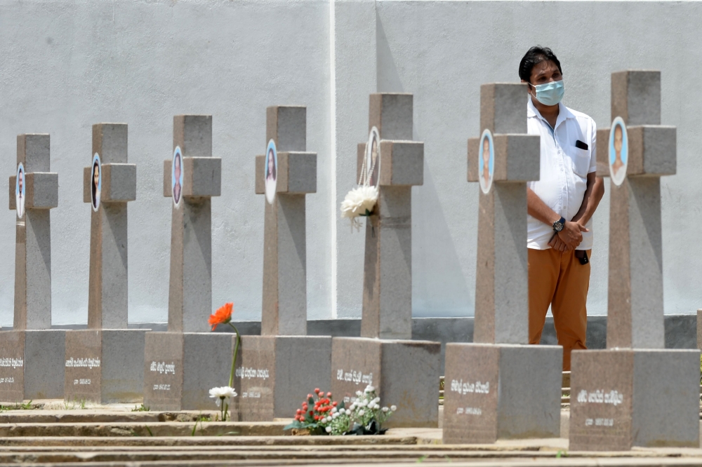 A relative pays his respect at a graveyard for St. Sebastian's Church bomb blasts victims in Negombo on April 21, 2020, to mark the first anniversary of the attacks. AFP / LAKRUWAN WANNIARACHCHI
