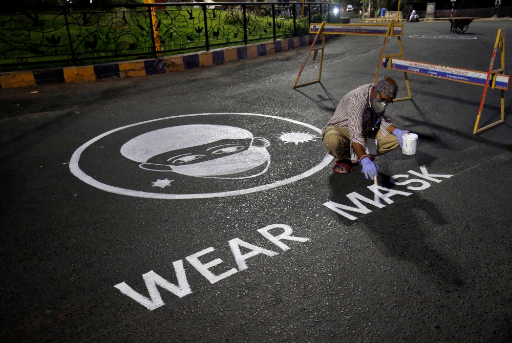 A man draws an awareness message on a road about wearing mask amid concerns about the spreading of coronavirus disease (COVID-19) in Ahmedabad, India, April 21, 2020. REUTERS/Amit Dave