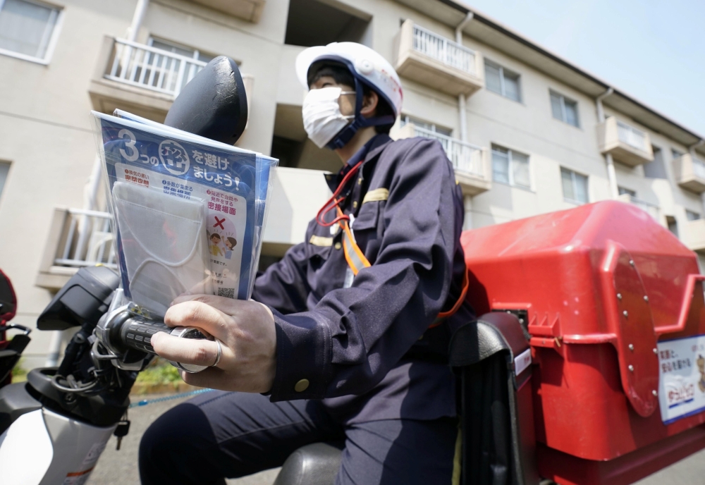 A mail carrier delivers cloth masks under a government program for the distribution of two washable masks each to all households in Japan to help contain the coronavirus disease (COVID-19) outbreak, in Tokyo, Japan April 17, 2020, in this photo taken by K