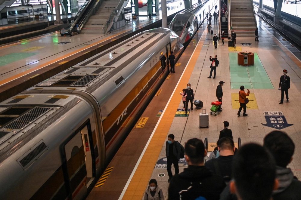 People wearing face masks as a preventive measure against the spread of the COVID-19 novel coronavirus arrive to board a train heading to Shanghai at Wuhan Railway Station in Wuhan, China's central Hubei province on April 21, 2020. / AFP / Hector RETAMAL