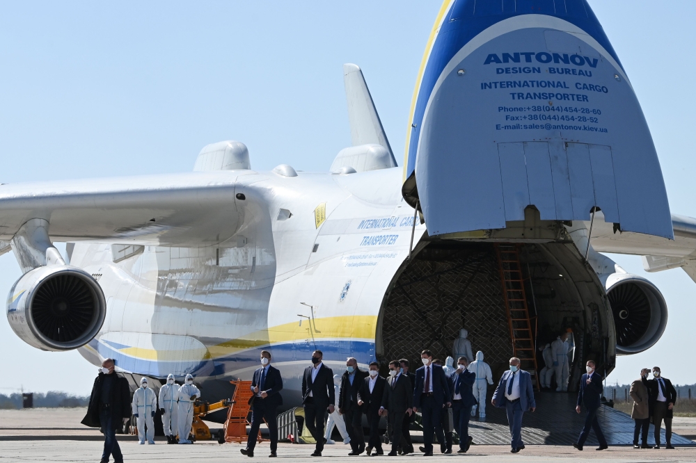 A group of officials, including President Volodymyr Zelensky, walk in front of an Antonov-225 Mriya cargo plane after its arrival with medical cargo from China, at an airfield in Gostomel outside Kiev on April 23, 2020, amid the COVID-19 coronavirus pande