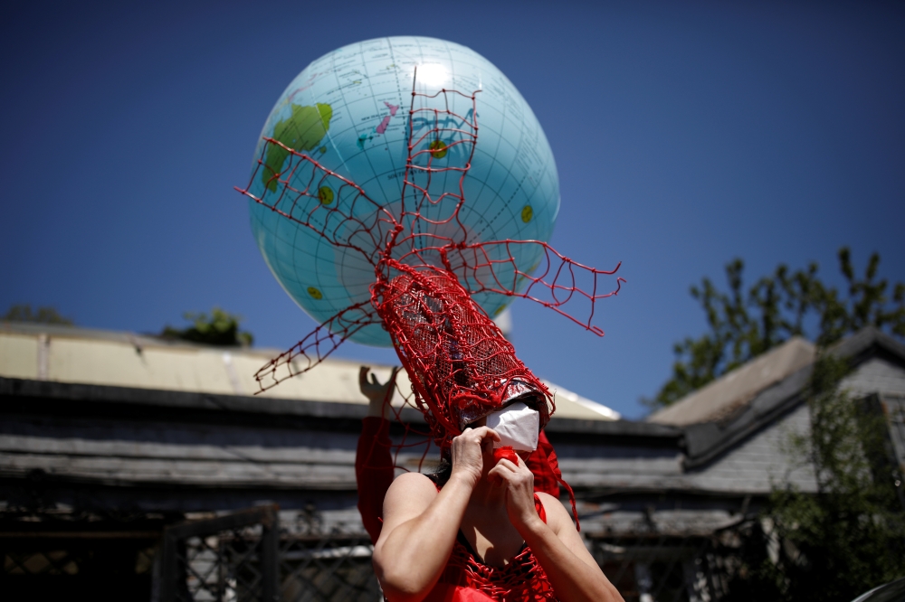Artist Kong Ning, wearing a face mask following the coronavirus disease (COVID-19) outbreak, prepares for a portrait in a wearable art piece she made to mark Earth Day, during a Reuters interview outside her studio in Beijing, China April 22, 2020. REUTER