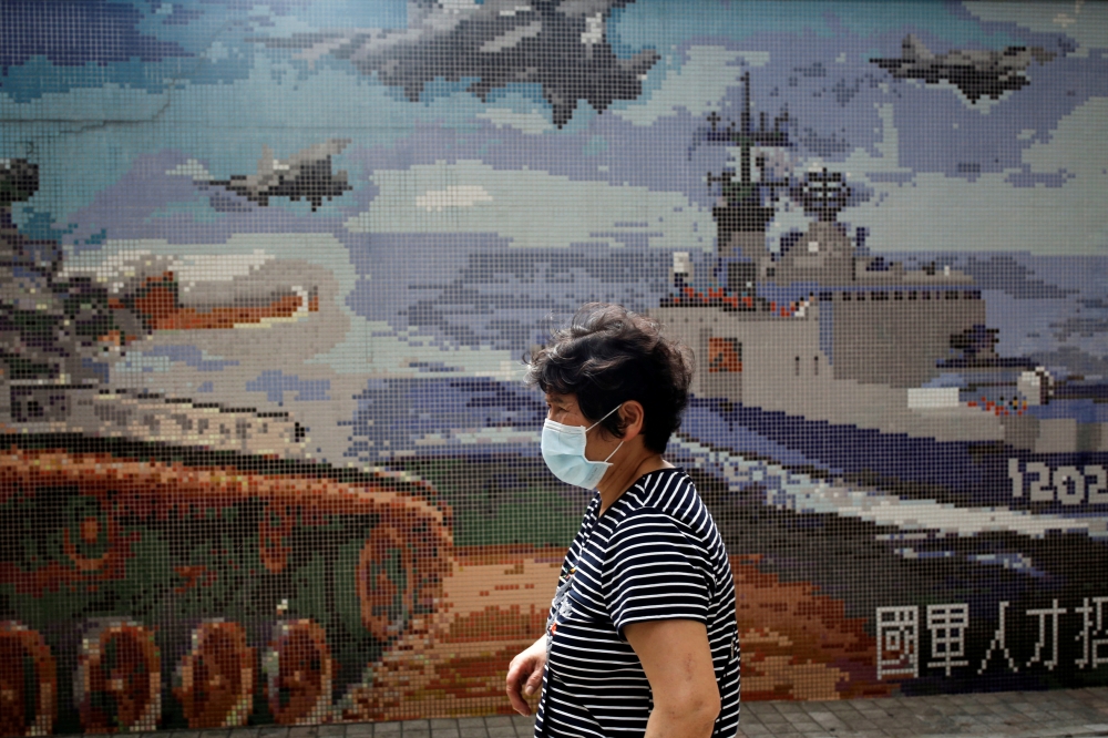 FILE PHOTO: A woman, wearing a protective face mask, walks past a Ministry of National Defense recruitment poster, amid concerns about the coronavirus disease (COVID-19), in Taipei, Taiwan, April 20, 2020. REUTERS/Ann Wang/File Photo
