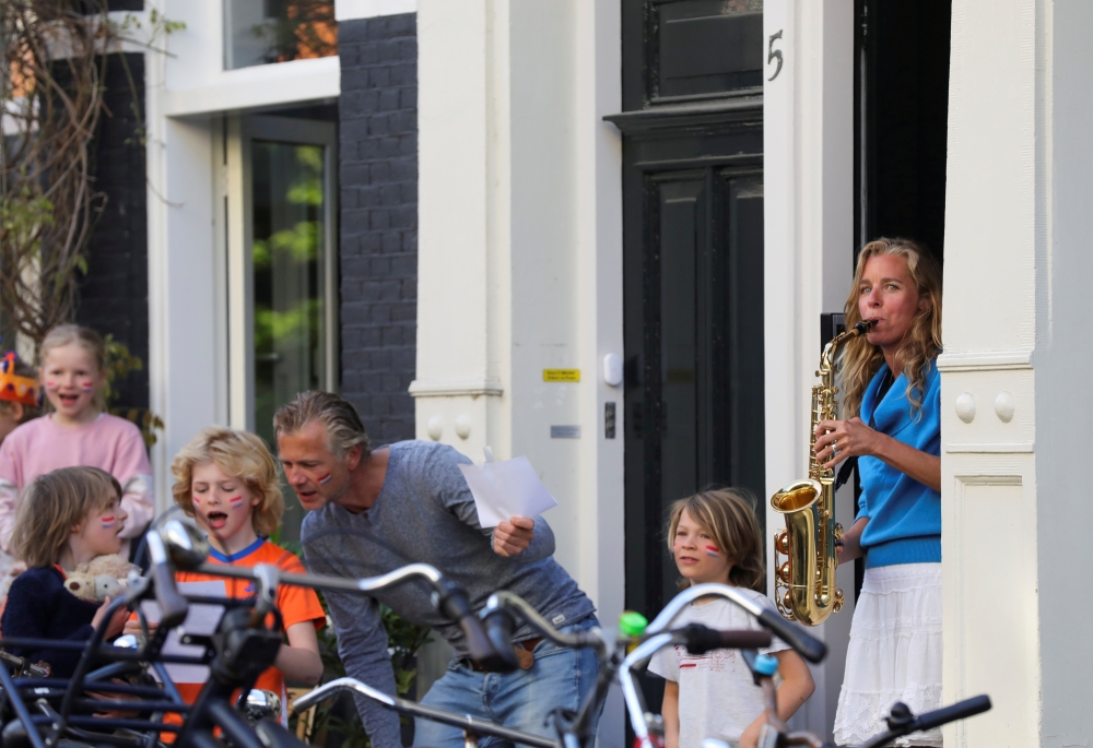 A member of the Royal Concertgebouw Orchestra plays the Dutch Wilhelmus anthem to celebrate King's Day (Koningsdag), as she stands on the doorway, during the coronavirus disease (COVID-19) outbreak in Amsterdam, Netherlands, April 27, 2020. REUTERS/Eva Pl