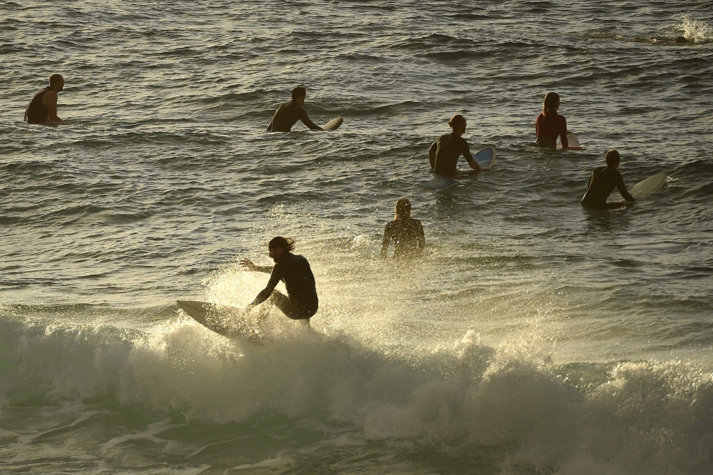 Surfers are seen in the ocean after Bondi Beach reopened following a five week closure in Sydney on April 28, 2020, amid the COVID-19 novel coronavirus pandemic./ AFP / PETER PARKS
