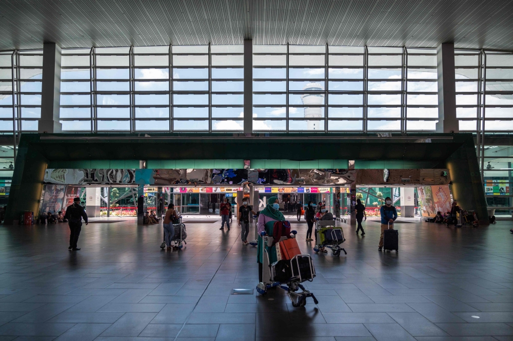 AirAsia passengers wearing face masks walk to the check-in counter at the Kuala Lumpur International Airport 2 in Sepang on April 29, 2020. / AFP / Mohd RASFAN