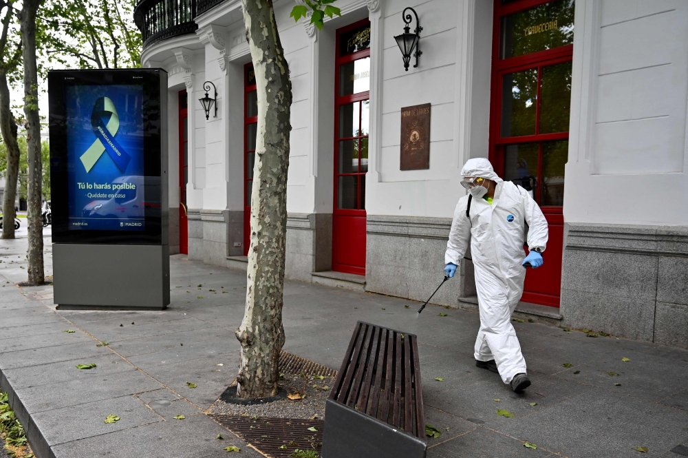 A worker disinfects a bench in Madrid on April 28, 2020 during a national lockdown to prevent the spread of the COVID-19 disease. Spain recorded a slight decrease in the number of daily coronavirus deaths with the government set to unveil plans to relax s