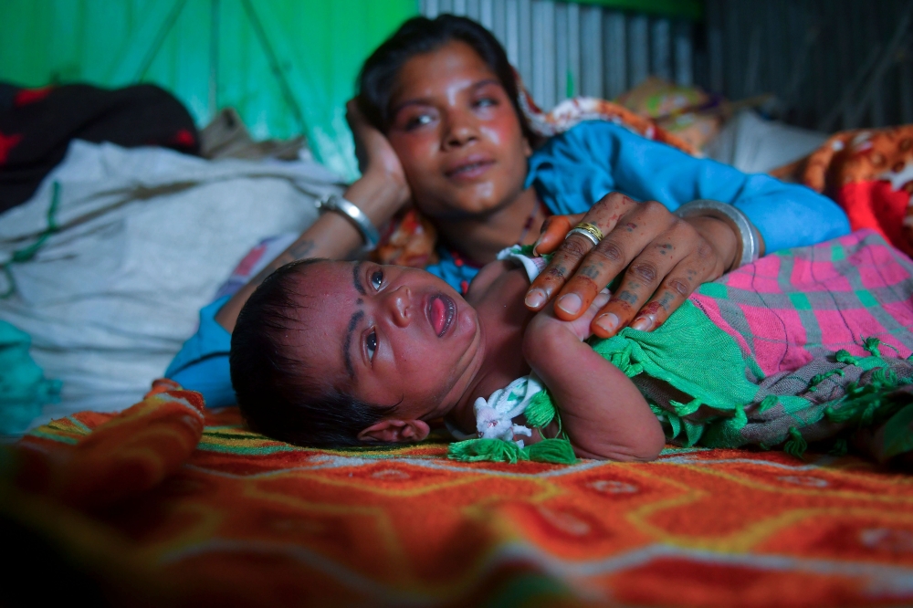 This picture taken on April 28, 2020, shows 23-year-old Manju Bauri resting next to her newborn baby boy named 'Lockdown' in their temporary rented quarter in Agartala. AFP / Abhisek Saha 