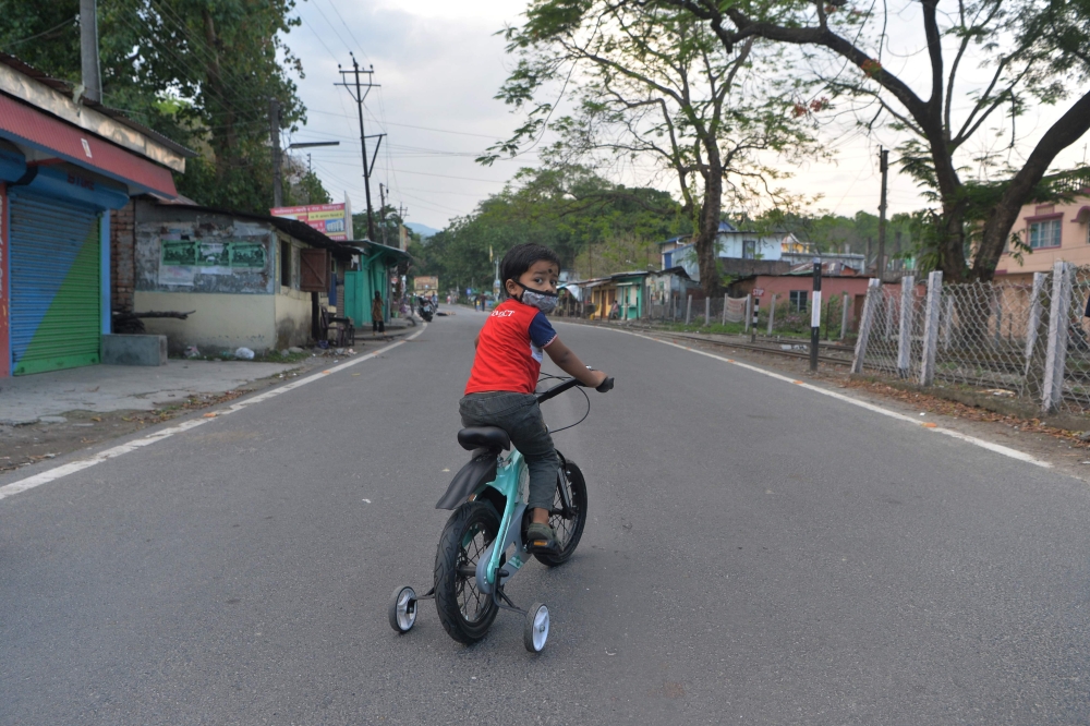 A boy rides a bicycle along a deserted National Highway 55 during a government-imposed nationwide lockdown as a preventive measure against the COVID-19 coronavirus, at Sukna on the outskirts of Siliguri on April 29, 2020. / AFP / DIPTENDU DUTTA
