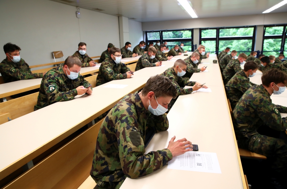 Swiss soldiers wearing protective face masks sit in a classroom as they install the contact tracking application created by the Swiss Federal Institute of Technology Lausanne (EPFL), using Bluetooth and a design called Decentralised Privacy-Preserving Pro