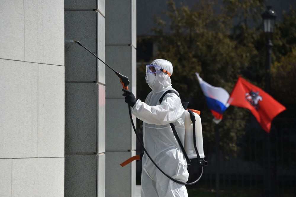 A municipal worker wearing a protective suit disinfects an office building in Moscow, on May 1, 2020 during a partial lockdown amid the COVID-19 outbreak caused by the novel coronavirus. / AFP / Vasily MAXIMOV